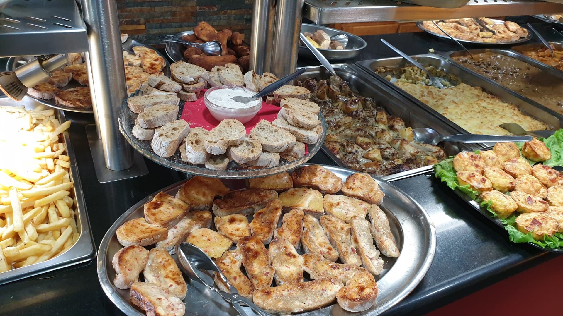 Travessas de carne, pão e batata frita no buffet